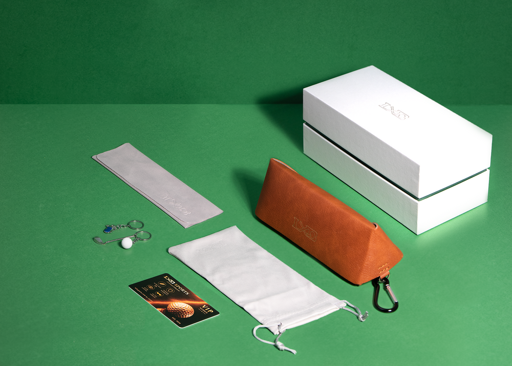 a white drawstring bag, a brown leather pouch, a white hard case, and a white box on a green background.
